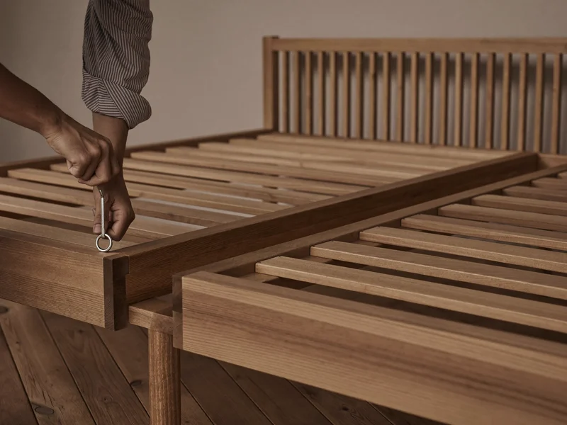 Illustration: Bettgestell wird mit Inbusschlüssel im ruhigen Schlafzimmer verschraubt